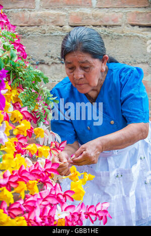 A Salvadoran woman decorates palm fronds with flowers during the Flower & Palm Festival in Panchimalco, El Salvador Stock Photo