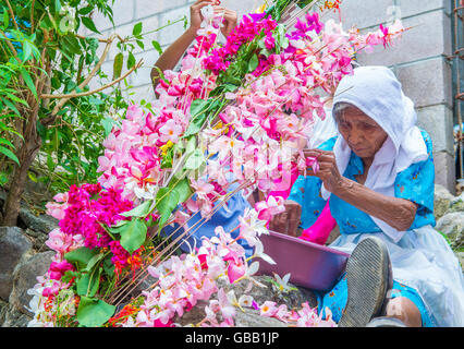 A Salvadoran woman decorates palm fronds with flowers during the Flower & Palm Festival in Panchimalco, El Salvador Stock Photo