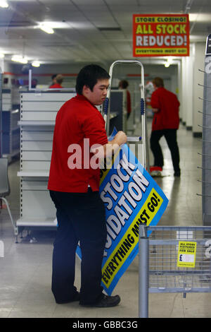 A staff member dismantles fixtures and fittings as Woolworths in Faversham, Kent, is one of around 200 stores closing today. Stock Photo