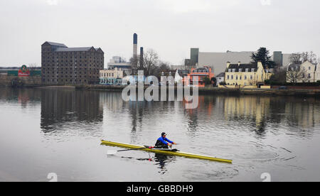 Rower Juliette Haig on the Thames passing the Stag Brewery at Mortlake. InBev have announced they plan to close the brewery in 2010. Stock Photo