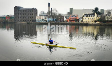 Rower Juliette Haig on the Thames passing the Stag Brewery at Mortlake. InBev have announced they plan to close the brewery in 2010. Stock Photo