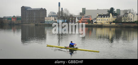 Rower Juliette Haig on the Thames passing the Stag Brewery at Mortlake. InBev have announced they plan to close the brewery in 2010. Stock Photo