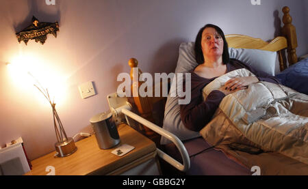 Terminally ill multiple sclerosis (MS) sufferer Val Mackay, who wants the right to die, in her bed at home in Perthshire with a grim reaper hanging on the wall. Stock Photo