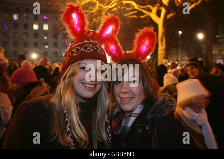 (left to right) Jess and Hannah Lyons, from Southampton in Hampshire, join thousands of other revellers enjoy themselves next to the River Thames opposite the London Eye and the Shell building, shortly before the capital was due to welcome in the New Year. Stock Photo