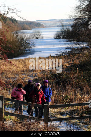 Walkers near the partially frozen Fewston Reservoir, near Harrogate, North Yorkshire. Stock Photo