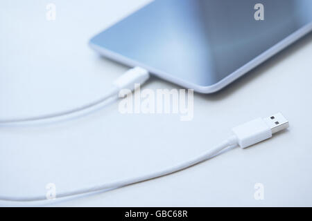 Tablet computer with USB cable laying on a table Stock Photo