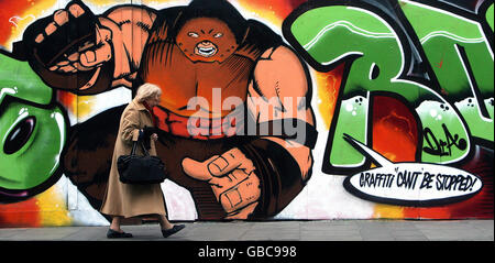 A woman walks past graffiti in the Portabello area of South Dublin. Stock Photo