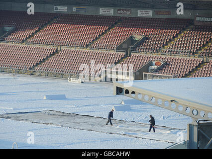 Groundstaff clear snow off the pitch at Northampton Town's Sixfields Stadium. Stock Photo