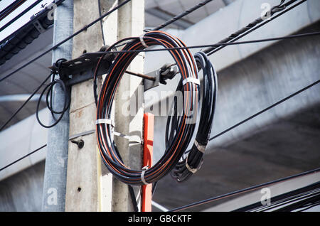 Many wires messy with power line cables, transformers and phone lines on old electricity pillar or Utility pole at beside road i Stock Photo