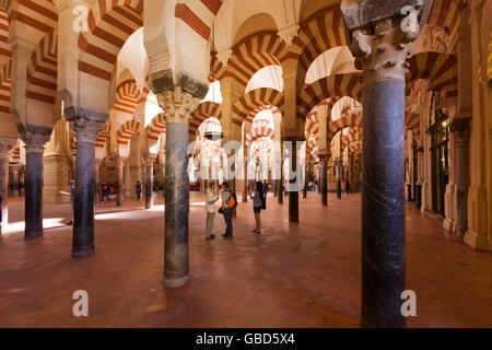 Visitors below the arches inside the Mosque-Cathedral of Córdoba, Spain