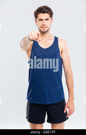 Confident young man athlete standing and pointing on you over white background Stock Photo
