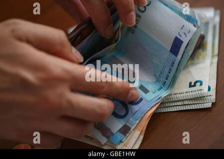 Woman opening brown leather wallet full of euro bank notes Stock Photo