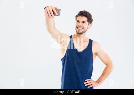 Happy young man athlete making selfie using mobile phone over white background Stock Photo