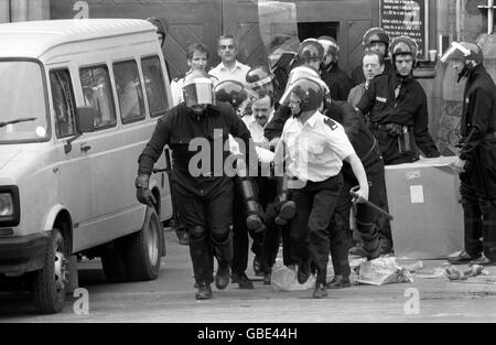 Police officers in riot gear rush a seriously injured colleague through the main entrance of Strangeways Prison, Manchester, during today's riots there. Stock Photo