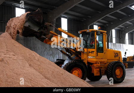 A JCB loads salt grit onto a gritting lorry at Whittlesford Depot in Cambridgeshire. Stock Photo