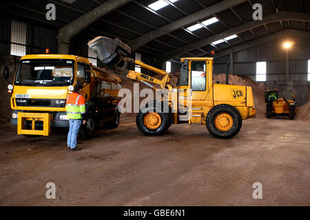 A JCB loads salt grit onto a gritting lorry at Wittlesford Depot in Cambridgeshire. Stock Photo