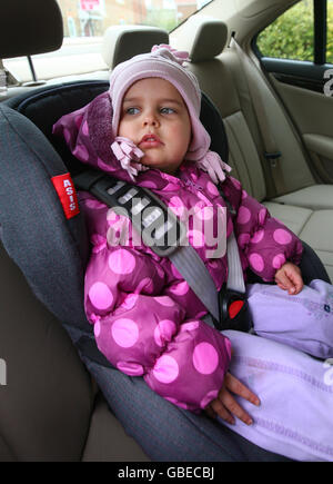 Child seat safety. A young girl prepares for a journey in a child's car seat near Ashford in Kent, as a survey reveals two in three car seats are not fitted properly. Stock Photo