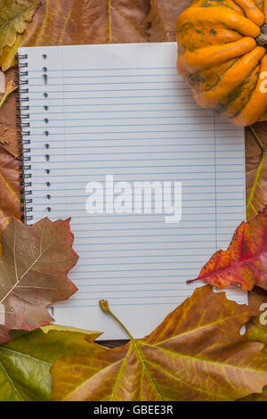 Notepad with autumn leaves and pumpkin on a wooden table Stock Photo