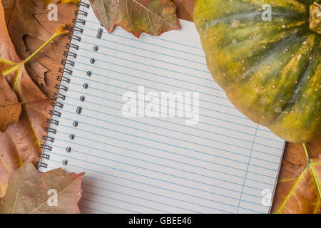 Notepad with autumn leaves and pumpkin on a wooden table Stock Photo