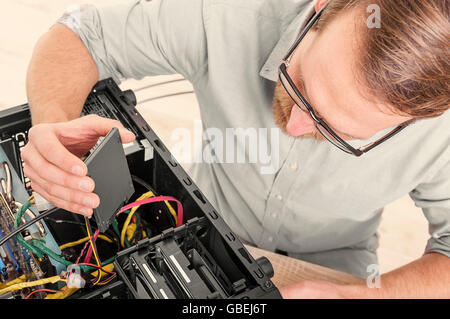 Engineer connects the SSD hard drive to the computer. Stock Photo