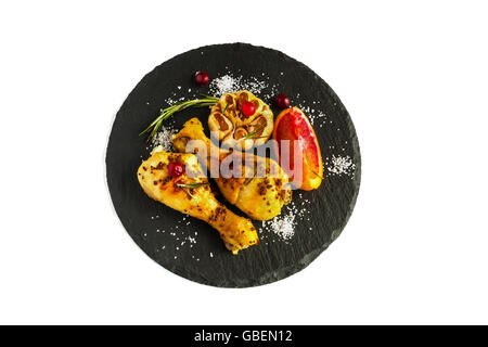 Roasted chicken legs, red oranges, cranberries, garlic and rosemary on the black background. Cooked with sauce from mustard, ora Stock Photo