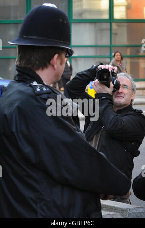 A photographer takes a picture of a policeman outside New Scotland Yard in London today as around 150 photographers held a mass photo shoot in protest at a new anti-terror law. Photojournalists say Section 76 of the Counter Terrorism Act, which became law today, could see them arrested for doing their job. Stock Photo