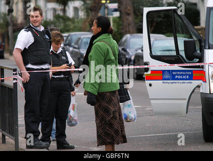 Man shot dead in London street. Police officers and residents at the scene of a shooting on Barry Road, in south-east London. Stock Photo