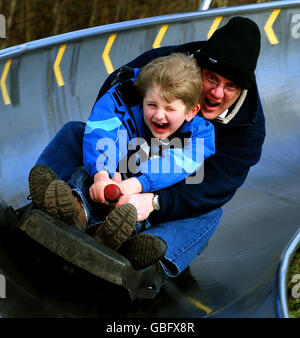 A man and his son (names not given) enjoy tobogganing during the warmer weather at Swadlincote Ski and Snowboard Centre, Swadlincote, Derbyshire. Stock Photo