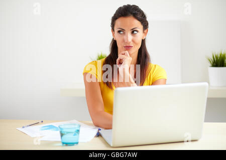 Pensive hispanic employee of a business company working on her laptop in the office - copyspace Stock Photo