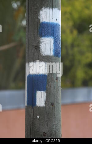 Trail Markers on a Telephone Pole.  Wooden Telephone pole with painted trail arrows for hiking trails. Waymarking marks in blue and white colors paint Stock Photo
