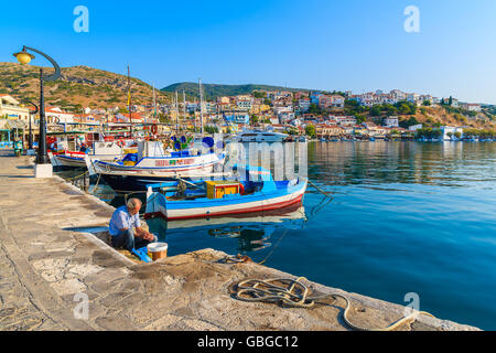 PYTHAGORION PORT, SAMOS ISLAND - SEP 19, 2015: fisherman is preparing freshly caught fish in beautiful Pythagorion port on Samos Stock Photo