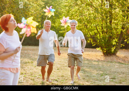 Seniors having fun in the park and holding pinwheels Stock Photo