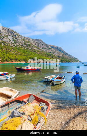 Fisherman standing among fishing boats on secluded beach, Samos island, Greece Stock Photo