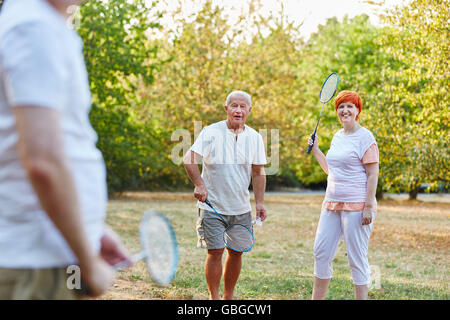 Group of seniors playing badminton in the park in summer Stock Photo