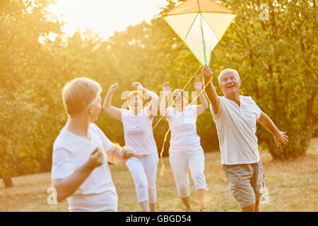 Seniors laughing and running while flying a kite Stock Photo