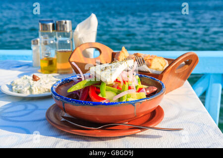 Greek salad on table in Greek tavern with blue sea water in background, Samos island, Greece Stock Photo