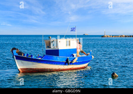 SAMOS ISLAND, GREECE - SEP 20, 2015: Greek fishing boat on blue sea with two fishermen on board, Samos island, Greece. Stock Photo