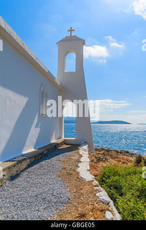 Tower of white Greek church in back light on coast of Samos island, Greece Stock Photo