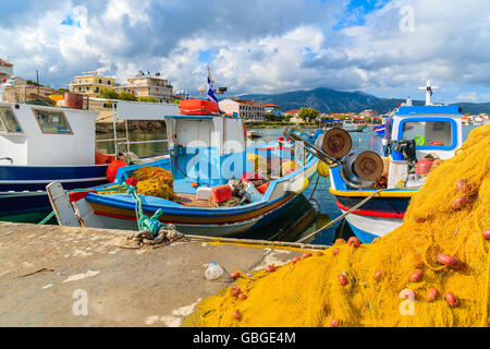 Fishing nets in foreground with Greek boats in port,in background Samos island, Greece Stock Photo