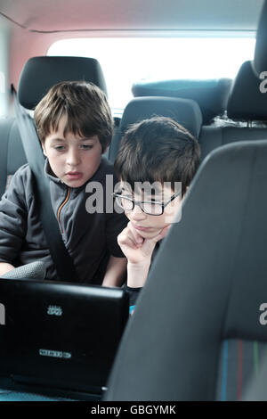 children watching DVD player in rear seat of car Stock Photo