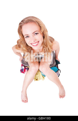 Pretty funny woman sitting on a suitcase with clothing in the studio Stock Photo