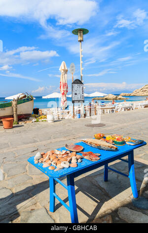 SAMOS ISLAND, GREECE - SEP 24, 2015: blue wooden stool with sea shells and souvenirs on beach in Kokkari town, Samos island, Gre Stock Photo
