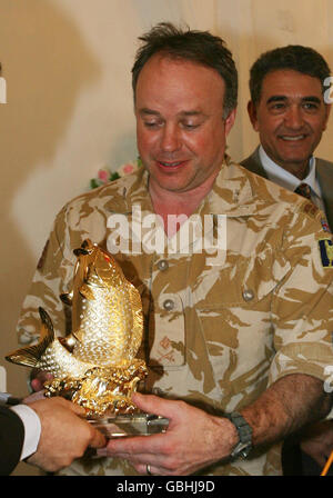 Major General Andy Salmon, head of coalition forces in Basra in southern Iraq smiles as he receives a golden jewel encrusted ornamental salmon at the Shatt Al Arab Hotel in Basra, Iraq, during part of a ceremony and feast put on by the Iraqi's to thank the British for their involvement in South East Iraq over the last 6 years. Stock Photo