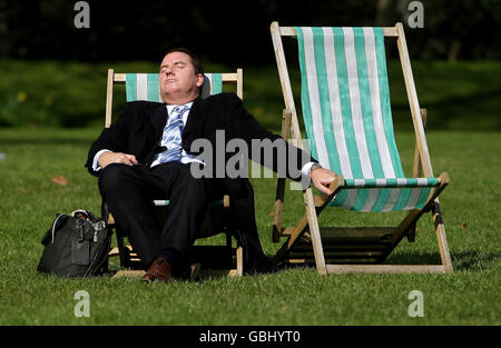 A man sleeps in the sun on a deckchair in Green Park, in central London, as the recent spell of warm weather continues in the capital. Stock Photo