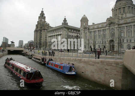 The first narrow boats pass in front of the famous Three Graces buildings in Liverpool, for the unveiling of the 22million Liverpool Canal Link. Stock Photo