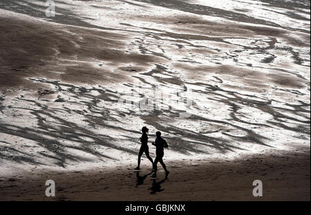 Joggers enjoy the warm temperatures on Tynemouth beach at Tyne and Wear on Easter Sunday. Stock Photo