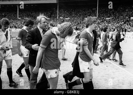 (L-R) Manchester United's Alex Forsyth, manager Tommy Docherty, Jimmy Greenhoff and Gerry Daly walk dejectedly off the pitch after losing 1-0 Stock Photo