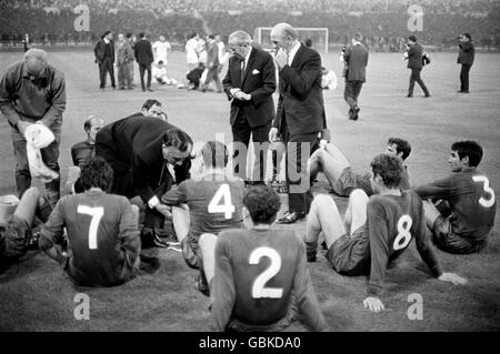 Manchester United manager Matt Busby (c, r) and his assistant Jimmy Murphy (l, leaning) try to inspire their players before the start of extra time Stock Photo