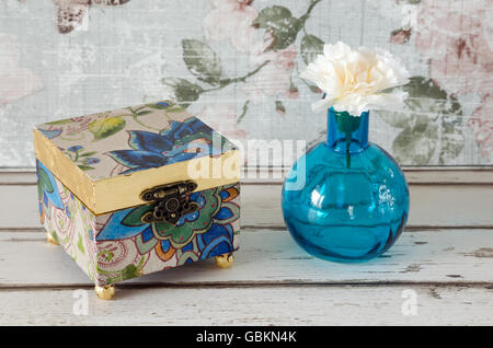 A handmade gilded trinket box with vase and flower on a shabby chic background Stock Photo