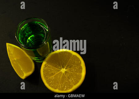 Absinthe and lemon on black background. Alcohol drink. Green alcohol drink Stock Photo